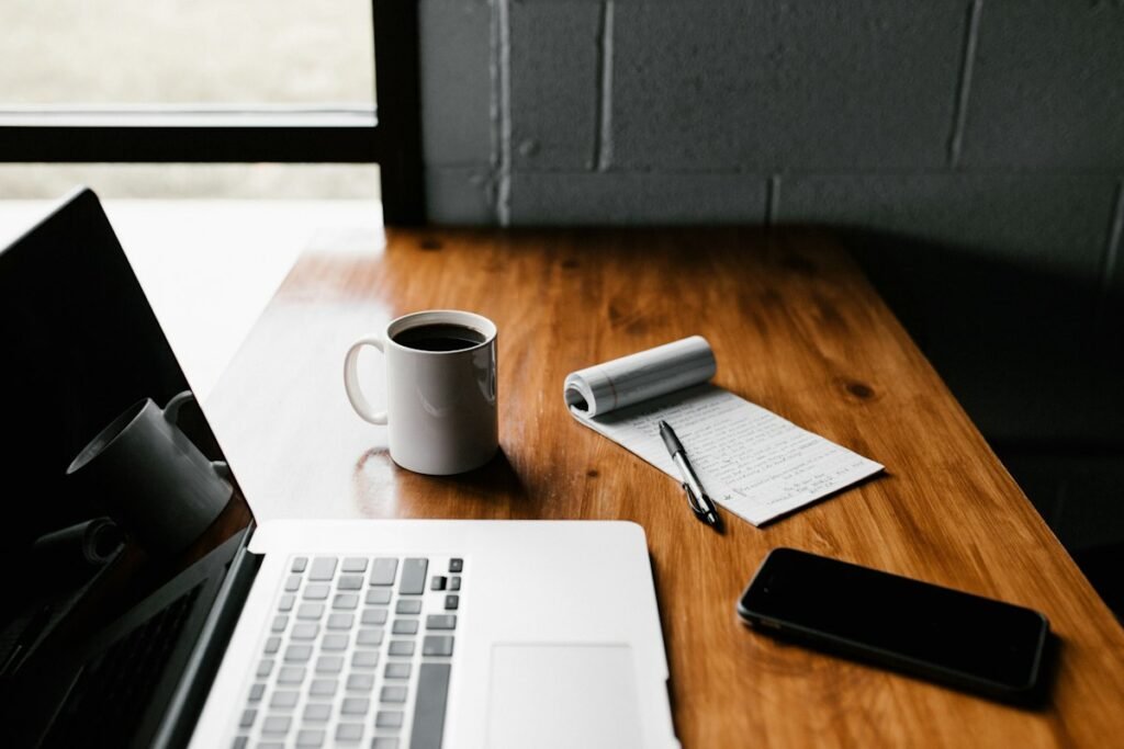 Laptop, smartphone, coffee and notebook on a wooden table